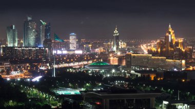 Sirk ve bayrağın aydınlatıldığı şehir merkezi ve merkez ticaret bölgesi üzerindeki gece görüşünün yükseltilmesi, Kazakistan, Nur-Sultan şehri, Orta Asya
