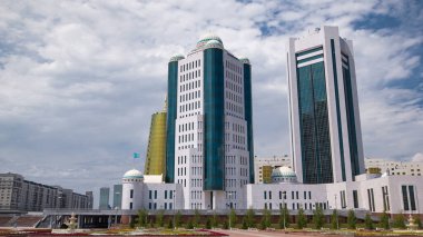 Nur-Sultan şehrinde Kazakistan Cumhuriyeti Senatosu 'nun binaları aşırı hız kazanmıştır. Ön planda çiçek açmış. Arka planda Nurzhol Bulvarı. Yazın mavi bulutlu gökyüzü