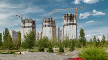 Turnalar, kırmızı çiçekler ve yeşil çimlerle zamanlanmış büyük bir inşaat alanının genel görünümü. Kazakistan 'ın Nur-Sultan şehrindeki Bağımsızlık Meydanı yakınlarında.