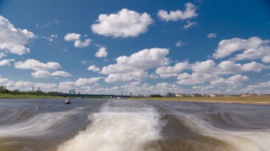 Astana, Kazakistan. Keyif teknesinden Astana 'da Ishim nehrinde hareketli bir seyahat görüntüsü. Mavi gökyüzü ve bulutlarla dolu bir yaz gününde. Bulanık hareket