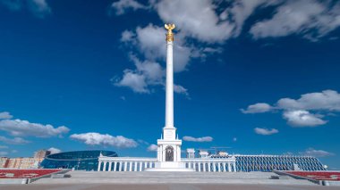 Kazakistan 'ın başkenti Astana' daki Independence Meydanı 'ndaki Kazak Eli Anıtı' nın zaman atlaması görüntüsü. Alttaki çiçek tarhında. Yaz günü mavi bulutlu bir gökyüzü. Nur-Sultan şehri