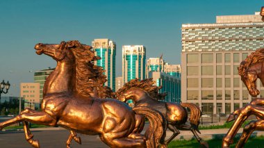 Atların heykelleri, Astana Opera Tiyatrosu 'nun önündeki yeşil çimlerde gün batımında, Kazakistan' da aşırı hızlanırlar. Nur-Sultan şehri