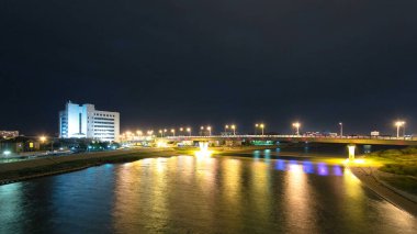 Atyrau City 'deki Ural Riverside' daki Modern Evler ve Aydınlanmış Köprü 'nün Zaman Hızlandırması. Bir Köprüden Hava Görüntüsü, Kazakistan 'da Şehir Zarafetinin Gece Parlamasını Gösteriyor