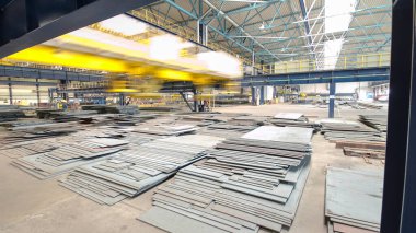 Vinç cihazını kaldıran fabrika atölyesi hiperhızlandırma, kaldırma mıknatısı, mekanik atölye, fabrika zemininde metal levha yapıları kullanarak yükleri kaldırma.