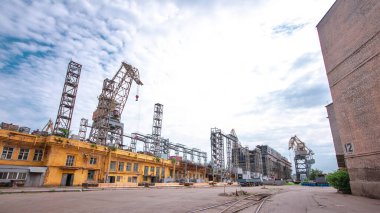 The construction of a large ship on a shipyard with cranes timelapse hyperlapse. A fragment of the case in the yellow workshop of the plant. Metal frame during assembly