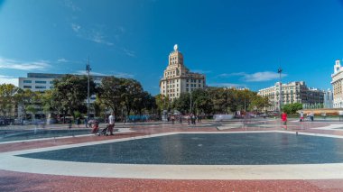 Hareketli Katalonya: Orta Barcelona 'daki Lively Placa de Catalunya' nın Zaman Hızı. İnsanlarla Dinamik Sahne, Merkezi Çeşme ve Büyük Saat 'in yer aldığı görkemli bir bina.