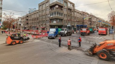 Traktör, yol onarım alanında zaman ayarlı. Yol yapım ekipmanları. Yol ayrımında inşaat işçileri var..