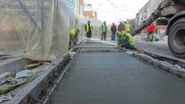 Çelik takviyesi yaptıktan sonra beton karıştırıcı zaman aşımına uğrayarak yolu hızlandırmak için hazır beton dökülüyor. Çadırla kaplı yeni raylar. Tramvay raylarının yeniden inşası