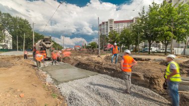 Beton, yol onarımı için birçok işçi ve mikser makinesiyle ezilmiş taş üzerinde çalışıyor. Tramvay raylarının yeniden inşası