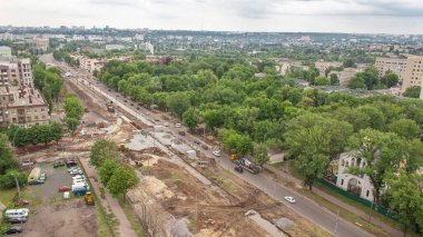 Buldozer panoramik hava görüntüsü, sanayi kamyonu kazıcı zemin hareket ediyor ve yol inşaatındaki bir çöp kamyonuna yükleniyor. Tramvay raylarının yeniden inşası