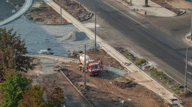 Betondaki karıştırma makinesi yol yapımında çalışıyor. Üniformalı zaman ayarlı birçok işçi var. Tramvay raylarının yeniden inşası. Havadan üst görünüm