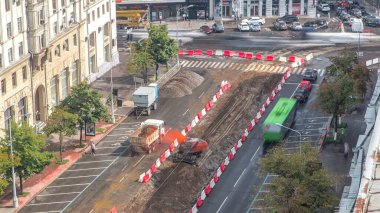 Endüstriyel kırmızı kazıcı toprağı taşıyor ve yol inşaatındaki bir çöp kamyonuna yüklüyor. Tramvay raylarının yeniden inşasının havadan görüntüsü