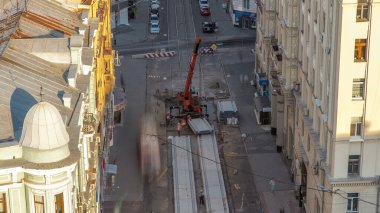 Yol inşaatı zamanındaki vinçle beton plaka montajının havadan görüntüsü. Şapkalı ve üniformalı endüstriyel işçiler. Şehir merkezindeki tramvay raylarının yeniden inşası.