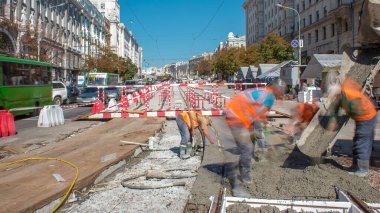 Beton, turuncu üniformalı ve mikser makineli işçilerle bir şehir merkezinde yol inşaatında çalışıyor. Tramvay raylarının yeniden inşası