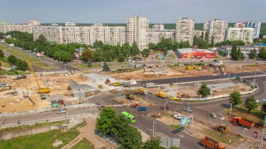 Birkaç endüstriyel makineli zaman ayarlı geniş yol şantiyesinin havadan görüntüsü. Toprak taşıma ekipmanları, kamyonlar ve vinçler. Yeni metro istasyonu binası