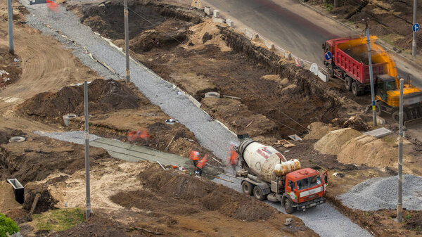 Concrete works for road construction with many workers in uniform, excavators and mixer machine timelapse. Reconstruction of tram tracks. Aerial top view