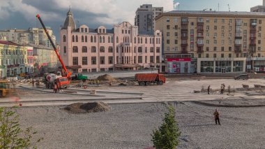 Beton, yol yapımında çalışıyor. Üniformalı zaman dilimi kullanan birçok işçi var. Karıştırıcı, vinç ve buldozer kavşakta çalışıyor. Tramvay raylarının yeniden inşası