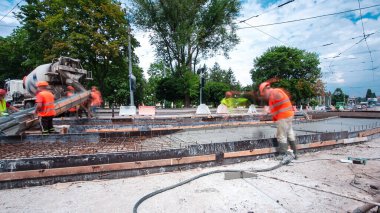 Tramvay rayları onarılan ve bakım süreleri yüksek olan yol inşaatı. Somut, kavşağın ortasında birçok işçiyle birlikte çalışır..