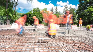 Tramvay rayları onarılan ve bakım süreleri yüksek olan yol inşaatı. Metal bir şebekeye beton dökülüyor. Kavşağın ortası..