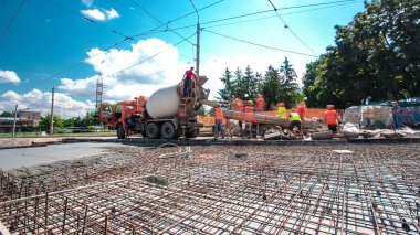 Tramvay rayları onarılan ve bakım süreleri yüksek olan yol inşaatı. Metal bir şebekede mikserden beton dökülüyor. Kavşağın ortası..