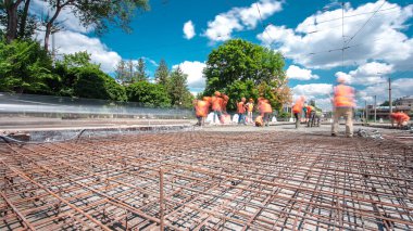 Tramvay rayları onarılan ve bakım süreleri yüksek olan yol inşaatı. Metal bir şebekeye beton dökülüyor. Birçok işçiyle kavşağın ortası.