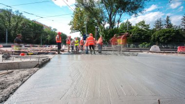 Tramvay rayları onarılan ve bakım süreleri yüksek olan yol inşaatı. Metal bir şebekeye taze beton dökülüyor. Kavşağın ortası..