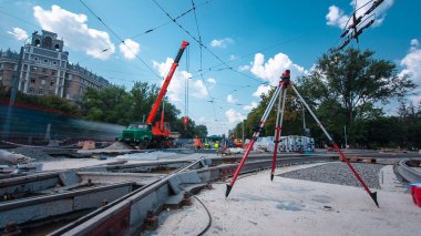 Tramvay rayları onarılan ve hiperhızlandırılmış yol inşaatı. Kavşağın ortasındaki tripodun elektronik seviyesi. Yeni toplu taşıma için demiryolu raylarının değiştirilmesi