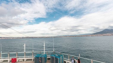 Dalgalı deniz manzarası ve açık deniz zaman diliminde yelken açan gemiden liman manzarası. Napoli kıyısı, İtalya