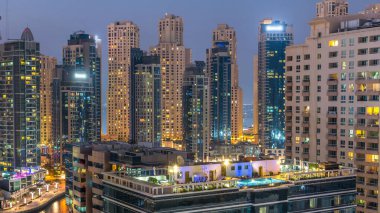 Dubai Yat Limanı hava görünümünü gece geçiş timelapse için bir noktadan günden güneş battıktan sonra. Modern gökdelenler ve konut kuleleri de akşam aydınlatılmış. Yolda trafik