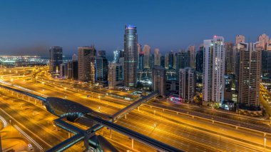 Dubai Yat Limanı gökdelenler hava üstten görünüm güneş doğmadan önce Jlt gelen Dubai gece gün timelapse, Birleşik Arap Emirlikleri için. Işıklı modern kuleleri ve Şeyh zayed yolu üzerinde trafik.