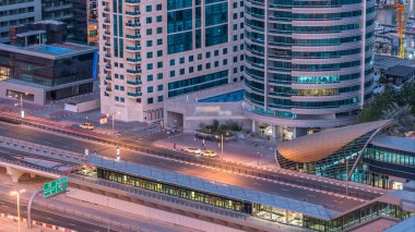 Dubai Yat Limanı gökdelenler ve tramvay istasyonu hava üstten görünüm güneş doğmadan önce Jlt gelen Dubai gece gün timelapse, Birleşik Arap Emirlikleri için. Işıklı modern kuleleri ve Şeyh zayed yolu üzerinde trafik.