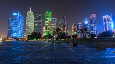 Doha 'nın yüksek katlı mahallesinde gece vakti hızlandırılmış hipervane, parktan görülmüş. Batı körfezinde aydınlatılmış gökdelenler ve palmiyeler