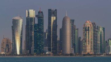 Arap şehri Doha 'nın ufuk çizgisi gece gündüz Katar' daki geçiş zamanı, gün doğumundan hemen önce aydınlık gökdelenlerle yakalandı. Corniche Gezinti Alanından Görünüm