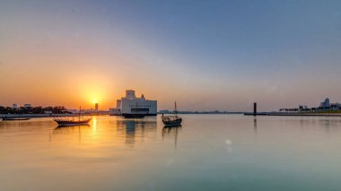 Katar 'ın Doha kentindeki İslam Sanatları Müzesi yakınlarındaki günbatımında, arkasında yükselen gökdelenler görülüyor. Öndeki eski tekneler.