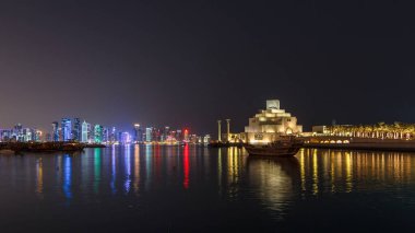 Katar 'ın Doha kentindeki eski dhow liman gecesi hiperhızının panoramik bir görüntüsü. Arka planda West Bay silueti var. Arka planda modern gökdelenler ve müzeler ve ön planda eski tekneler