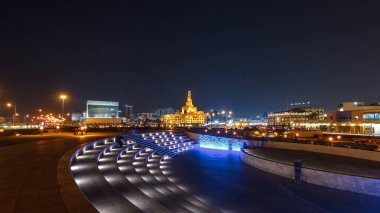 Souq Waqif Parkı 'ndaki küçük amfi tiyatro Doha' da gece vakti hızlandırılmış hiperhızlandırma, bitki örtüsü ve uzak mesafedeki binalar, aydınlatılmış İslam merkezi de dahil olmak üzere.