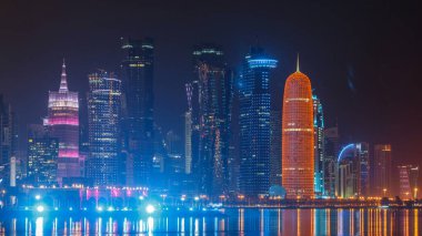 Geleneksel dhow botu Doha 'da, arka planında modern binalar olan gece zaman diliminde. Batı körfezinde aydınlık gökdelenler.