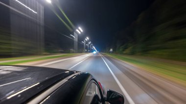 Otobanın en üst kısmından sürtünme gece otobanında süratle ilerliyor. Işıklar arabayı yüksek hızda yansıtıyor. Modern bir şehrin hızlı ritmi. Bulanık hareket