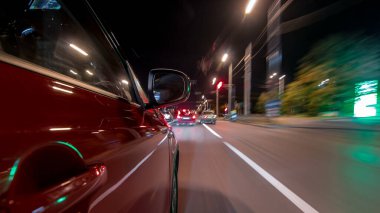 Hızlı arabanın yanından gelen bir drivelapse, gece caddesinde hızla ilerliyor. Işıklar yüksek hızda arabayı yansıtıyor. Modern bir şehrin hızlı ritmi. Bulanık hareket