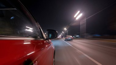 Hızlı sürüş yapan bir şehrin gece caddesinde, yüksek hızda ışık yansıtan bir yolda, hızlı sürüş yapan bir arabadan saçma sapan bir şehir görüntüsü. Modern bir şehrin hızlı ritmi. Bulanık hareket