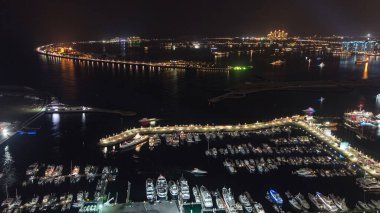 Dubai Marina Panorama 'dan Palm Jumeirah Adası' na hava görüntüsü. Yukarıdan aydınlık oteller ve villalar görünüyor. Limandaki yatlar ve tekneler