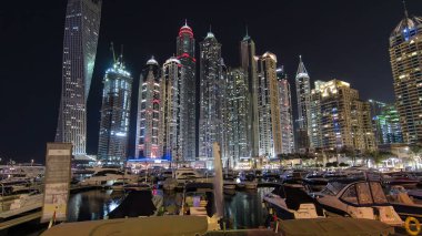 Dubai Marina 'nın en yüksek gökdelenleri, konut kuleleri ve tekneleriyle liman gecesi Dubai, Birleşik Arap Emirlikleri' nde hiper hız.