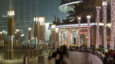 Dubai, BAE 'deki çeşmenin yanında yürüyüş alanı. İnsan yapımı gölde aydınlatılmış palmiyeler ve sokak lambaları