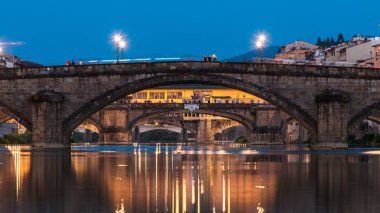 Alacakaranlık sahnesi Ponte Alla Carraia ve Santa Trinita (Kutsal Üçlü Köprü) gece gündüz Arno Nehri üzerinde geçiş zamanı günbatımından sonra suya yansıyan yansımalarla. Floransa, Toskana, İtalya