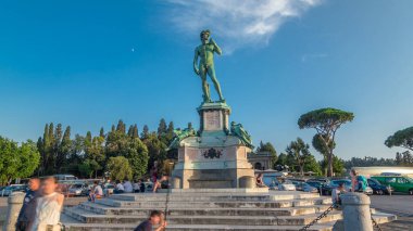 Michelangelo 'nun Floransa' daki Piazzale Michelangelo zaman tünelinde yaptığı David heykelinin bronz kopyası. Yaz günü yeşil ağaçlar ve mavi gökyüzü. Etrafta dolaşan insanlar