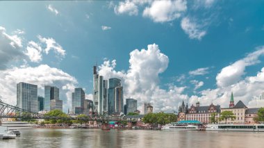 Almanya 'nın Frankfurt kentindeki ana nehrin üzerindeki tarihi Eiserner Steg' in (Demir Köprü) hiperlapesi. Gökdelenler ufuk çizgisi ve tarihi binalar bulutlarla dolu bir zaman dilimi altında suya yansıyor.