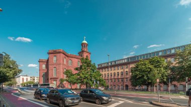 Frankfurt, Almanya 'da St. Paul Kilisesi (Paulskirche) zaman atlaması. Protestan kilisesi Paulplaz 'da duruyor. Bulutlarla kaplı mavi gökyüzünün altındaki bu tarihi anıtın etrafında sokak trafiği akıyor.