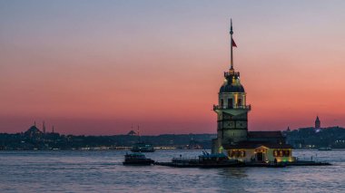 Bakireler gün batımından geceye İstanbul 'da, Türkiye' de, Kiz Kulesi 'nde geçiş zamanları. Arka planda şehrin ufuk çizgisi Bosforus suyuna yansıyor