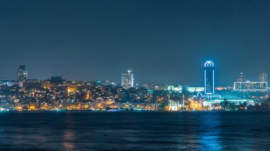 Night timelapse view of besiktas district with some illuminated skyscrapers and mosque in Istanbul taken from asian part of the city. Reflection on Bosphorus water