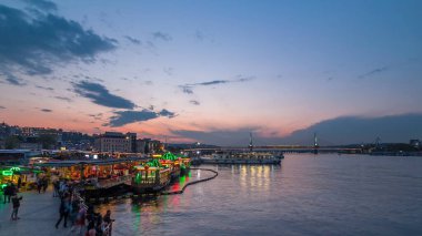 İstanbul 'un İstanbul silueti, gün batımından sonra İstanbul' da, İstanbul Boğazı 'ndaki Golden Horn' da tekne istasyonu yakınlarındaki yolcu feribotları. Arka plandaki cami ve köprü bahar günündeki su yansıması ile